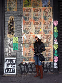 Full length of woman standing against graffiti wall