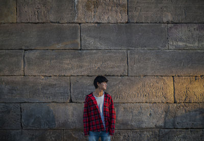 Portrait of asian teenage boy standinging against stone wall