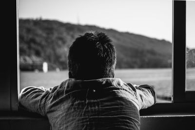 Rear view of man looking through window