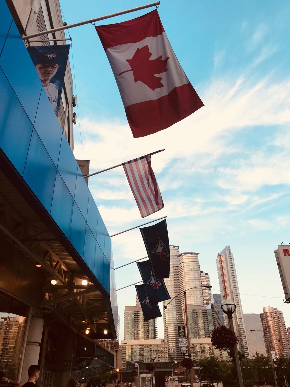 building exterior, built structure, architecture, low angle view, city, sky, flag, building, patriotism, cloud - sky, nature, no people, office building exterior, day, office, outdoors, skyscraper, red, environment, wind, financial district, national icon