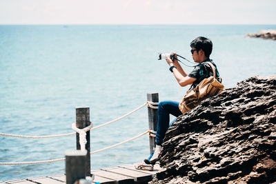 Man photographing on sea against sky