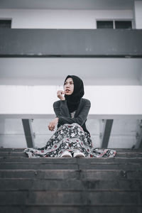 Portrait of woman sitting against wall