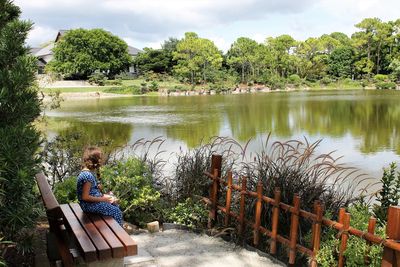 People sitting by lake against trees