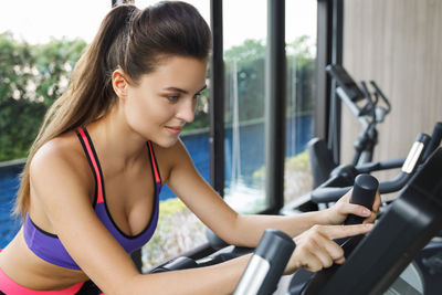 Side view of young woman exercising in gym
