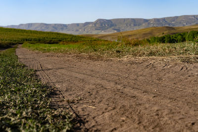 Surface level of road amidst field against sky