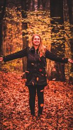 Full length of woman standing on autumn leaves