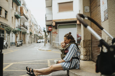 Mother with baby sitting on street