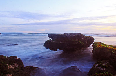 Rock formation on sea against sky during sunset