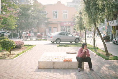 Full length of man sitting on street in city