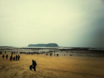 People at beach against clear sky