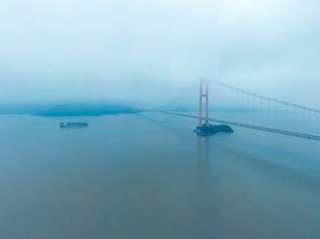 Suspension bridge over sea against sky