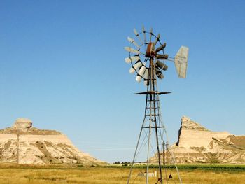 American-style windmill on field against clear blue sky