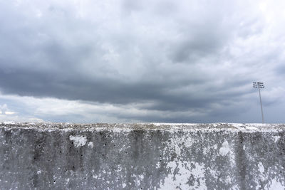 Low angle view of snow on wall against sky