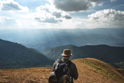 Rear view of man standing on mountain against sky