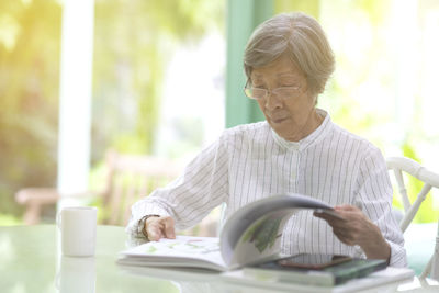 Senior woman reading book sitting at home