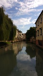 Canal amidst buildings against sky