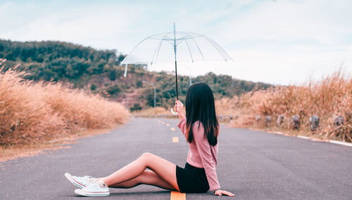 Side view of woman sitting on road