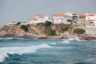 Buildings by sea against clear sky