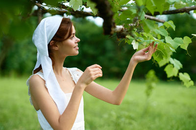 Side view of young woman with arms raised standing on field