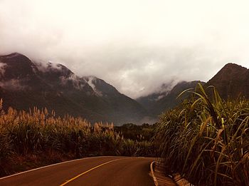 Road leading towards mountains against sky