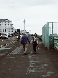 Rear view of people walking on road in city