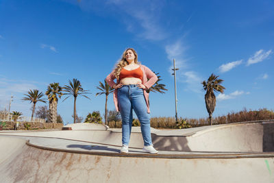 Full length of young woman standing against sky