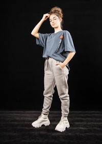 Portrait of teenage boy standing against black background