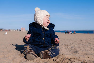 Extatic young boy is playing in the sand during in cold weather