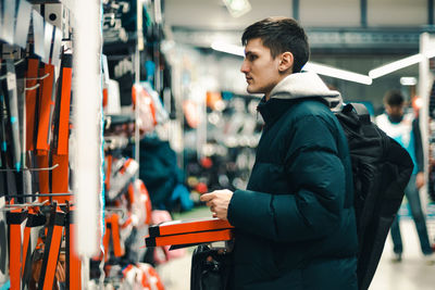 A young guy chooses a backpack in a store.