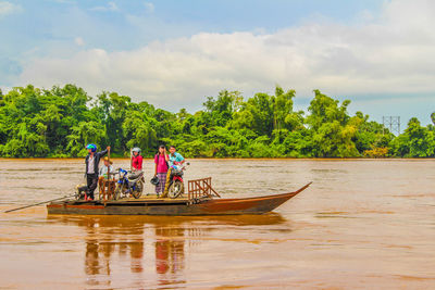 People in boat on river against sky