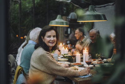 Portrait of smiling senior woman enjoying with friends during dinner party