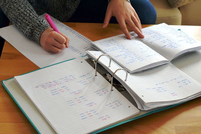 High angle view of woman writing on paper over table