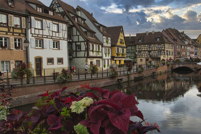 View of canal by buildings against cloudy sky