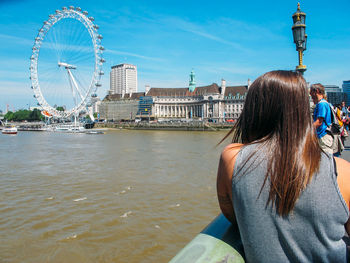 Rear view of woman in city by river during summer