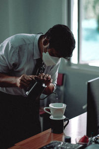 Side view of young man using mobile phone at table