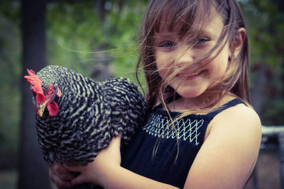 Close-up portrait of smiling girl holding chicken bird