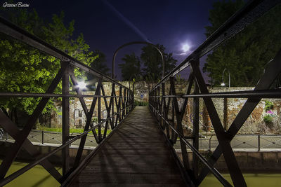 Surface level of footbridge against illuminated bridge