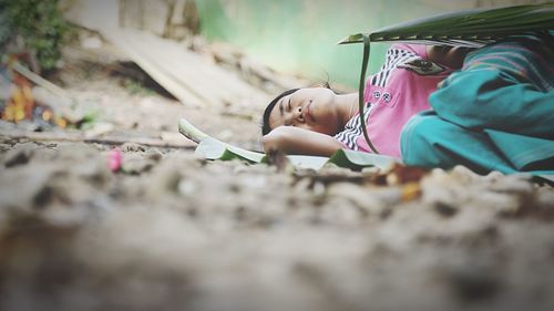 Surface level view of woman sleeping on ground