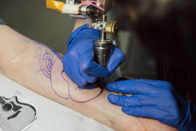 Artist tattooing on hand at studio