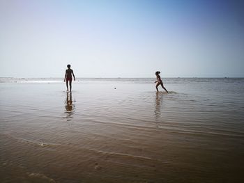 People enjoying on beach against clear sky