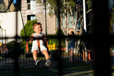 Smiling baby girl swinging in playground