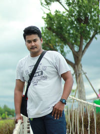 Portrait of young man standing against trees