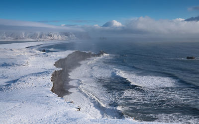 Panoramic image of the coastal landscape of cape dyrholaey with snow-covered coastline, iceland