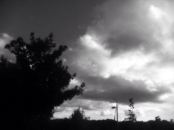 Low angle view of silhouette trees against cloudy sky