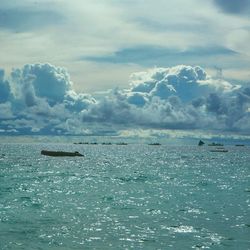 Boat sailing in sea against cloudy sky