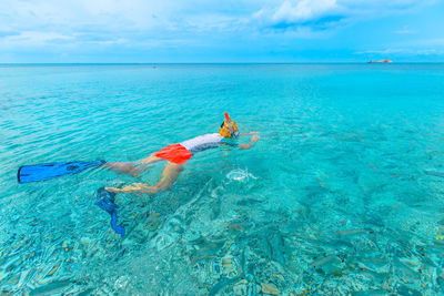 Person swimming in sea against sky