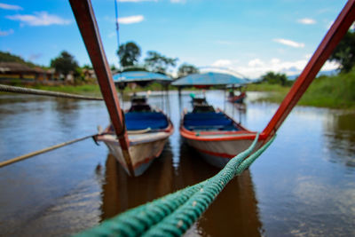 Boats moored on river against sky