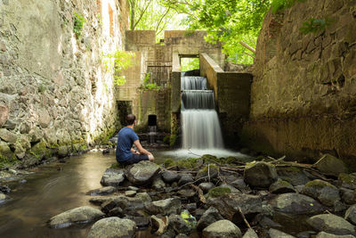 Woman sitting on rock by river