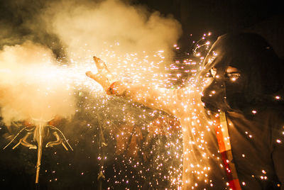 Low angle view of person and firework display at night