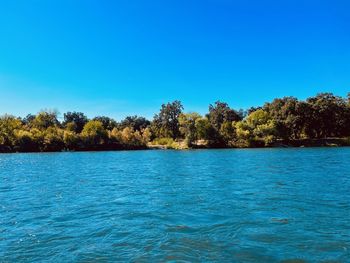 Scenic view of lake against clear blue sky